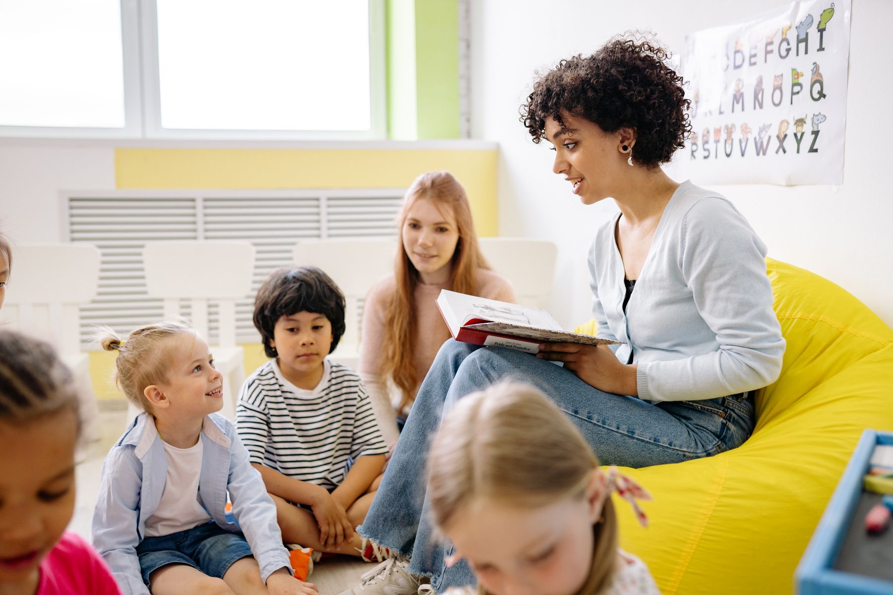 An adult reading a book with children in a childcare setting